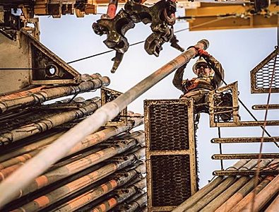 An H&P Derrickman directs pipe on a drilling rig.